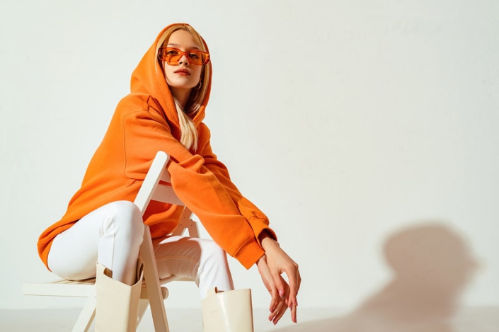 Junge Frau in lässigem orangefarbenem Hoodie und weißer Hose, für eine entspannte Casual Stilberatung in Hannover.